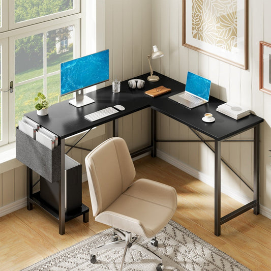 Black L-shaped corner desk with metal frame, dual monitor setup, and storage shelves in bright home office.